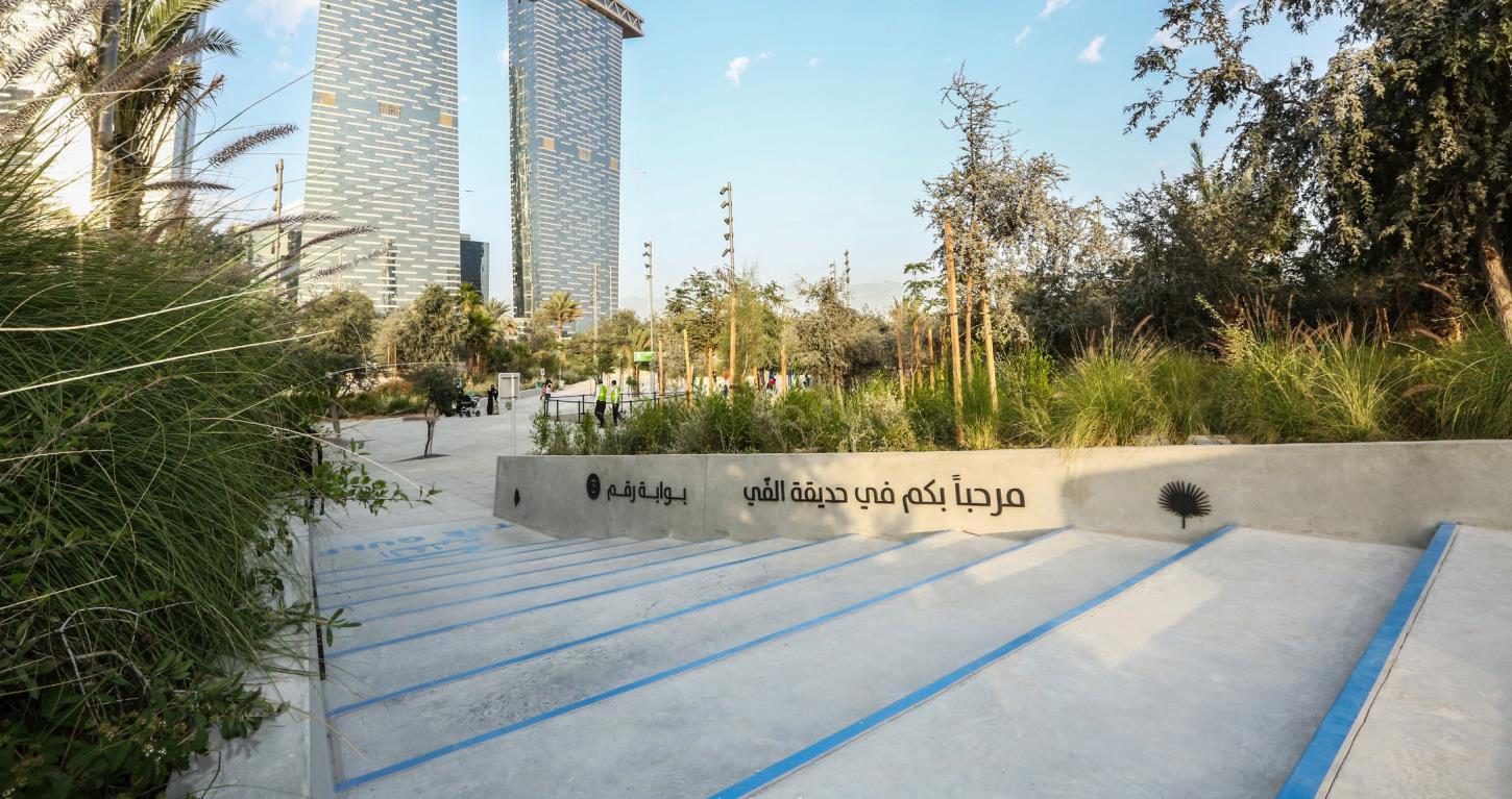 Planted urban public realm framed by mature trees and landscape